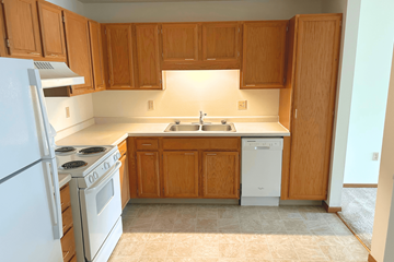 Mounds View apartment for rent - A kitchen with wooden cabinets and a white dishwasher.