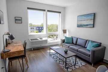 Richfield apartment for rent - A living room with a brown couch, a wooden desk, and a painting on the wall.