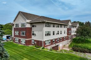 Mounds View apartment for rent - A large two-story building with a red brick facade and a grey roof.