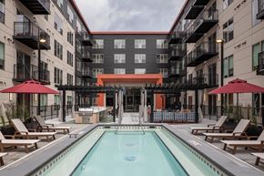 St Paul apartment for rent - A swimming pool surrounded by lounge chairs and umbrellas in a courtyard.