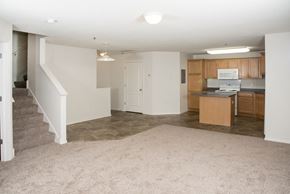 Maplewood townhouse for rent - an empty living room and kitchen with a stairway to a room with wood cabinets