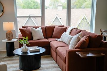 Wayzata apartment for rent - A living room with a red couch and a round table with a plant on it.
