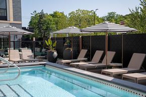 Wayzata apartment for rent - A pool with chairs and umbrellas is surrounded by a black fence.