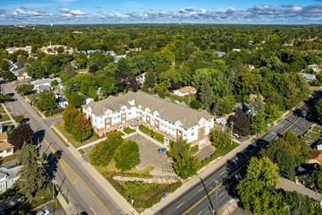 Saint Paul apartment for rent - An aerial view of a large white building surrounded by trees and a road in front.