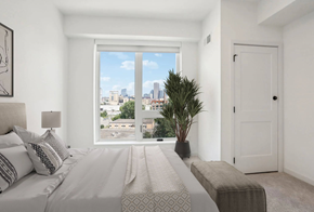 Minneapolis apartment for rent - A bedroom with a large bed and a view of the city.
