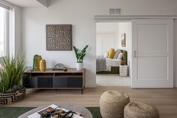 Minneapolis apartment for rent - A living room with a brown and white cabinet, a green rug, and a large abstract painting on the wall.
