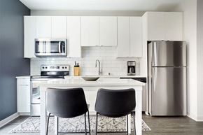 Minneapolis apartment for rent - a white kitchen with black chairs and a stainless steel refrigerator