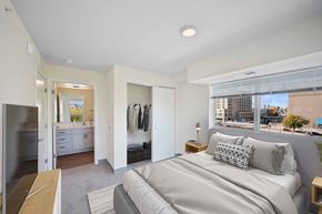 Minneapolis apartment for rent - A bedroom with a large bed and a view of the city.