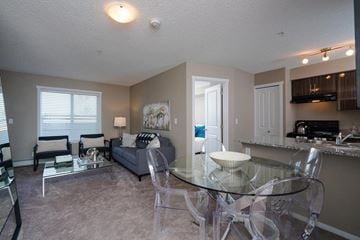 Edmonton apartment for rent - A living room with a glass table and chairs.