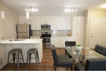 Edmonton apartment for rent - A modern kitchen with a glass table and bar stools.