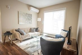Edmonton apartment for rent - A living room with a grey sofa, a glass coffee table, and a television.