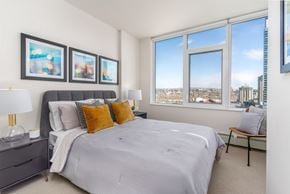 Calgary apartment for rent - A bedroom with a large bed and a view of the city.