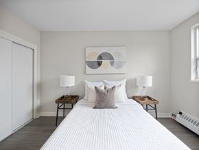 Toronto apartment for rent - A bedroom with a large bed, two lamps, and a painting on the wall.