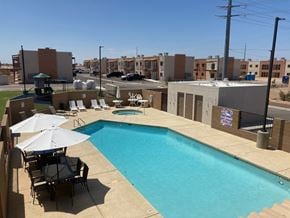 Yuma apartment for rent - a swimming pool on the roof of a building with chairs and umbrellas