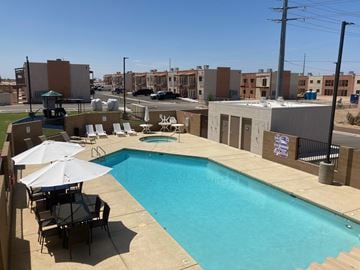 Yuma apartment for rent - a swimming pool on the roof of a building with chairs and umbrellas