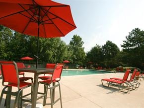Taylor townhouse for rent - A red umbrella is in the foreground of a poolside table.