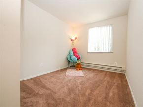 Taylor apartment for rent - A room with a carpet, a chair, a lamp, and a window.