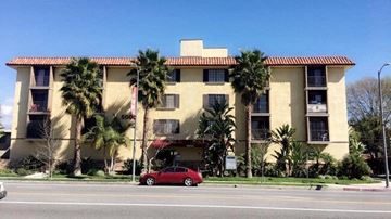 Valley Village apartment for rent - a red car parked in front of a building with palm trees
