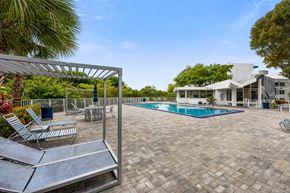 Miami apartment for rent - a swimming pool with chairs and a house in the background