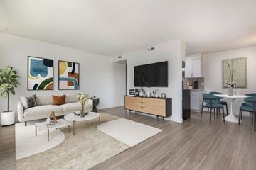 Northglenn apartment for rent - A living room with a white couch, a coffee table, a TV, and a dining table with chairs.
