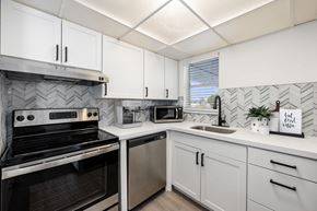 Miami apartment for rent - a kitchen with white cabinets and black and white appliances