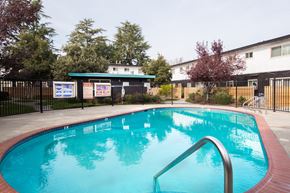 Fremont apartment for rent - a swimming pool with a fence and buildings in the background
