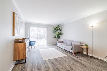 Birmingham apartment for rent - A living room with a grey couch, a wooden cabinet, and a small table with a plant on it.