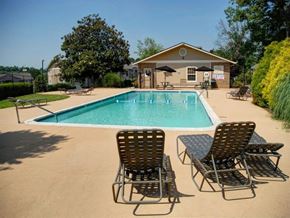 Knoxville apartment for rent - a pool with chairs and a house in the background