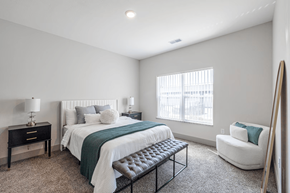 Norton Shores apartment for rent - A bedroom with a bed, chair, and nightstand.