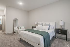 Allendale Charter Twp apartment for rent - A bedroom with a large bed and a nightstand with a lamp.