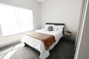 Norton Shores apartment for rent - A bedroom with a large bed and a small table with a plant on it.