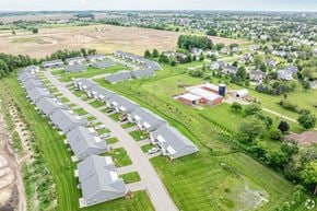 Hudsonville apartment for rent - A large, modern building is surrounded by a long row of houses.