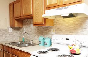 Baltimore apartment for rent - a kitchen with wood cabinets and white appliances