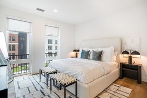 Newton apartment for rent - A bedroom with a large bed and a balcony with a view of a building.