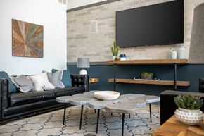Columbus apartment for rent - A living room with a black couch, a round table, and a flat screen TV mounted on the wall.