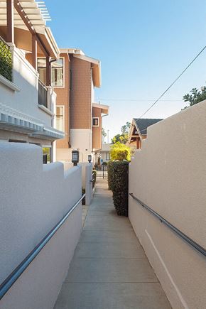 Ventura condo for rent - A narrow alley with a white wall on one side and a building on the other.