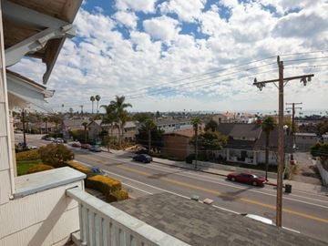 Ventura apartment for rent - A red car is driving down a street with a white car parked on the side.