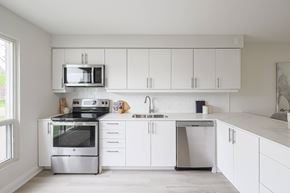Oshawa apartment for rent - A modern kitchen with white cabinets and stainless steel appliances.
