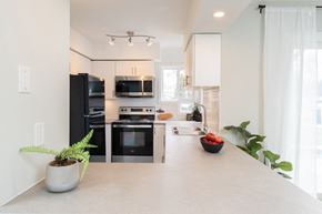 Oshawa apartment for rent - a kitchen with white cabinets and black appliances