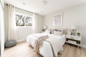 Oshawa apartment for rent - a bedroom with a large window and a bed with a white comforter and pillows