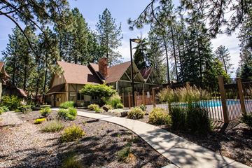 Spokane apartment for rent - A house with a brown roof is surrounded by trees and has a pool in the backyard.