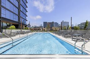 Chicago apartment for rent - a swimming pool with lounge chairs next to a building with a city in the background