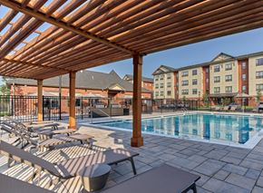 Dunellen apartment for rent - A wooden pergola shades a swimming pool and lounge chairs.