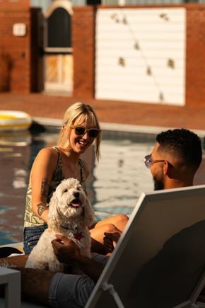Lancaster apartment for rent - A woman and a man are sitting by a pool with a dog, looking at a laptop.