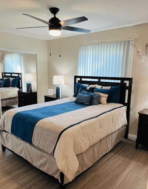 Riverside apartment for rent - A bedroom with a large bed and a ceiling fan.