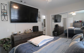 Riverside apartment for rent - A bedroom with a large bed and a flat screen TV mounted on the wall.