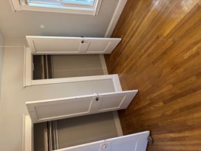 Jamaica Plain apartment for rent - A wooden staircase with a white railing and a skylight above.