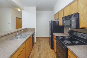 Spokane apartment for rent - a kitchen with a black stove top oven next to a sink and a refrigerator