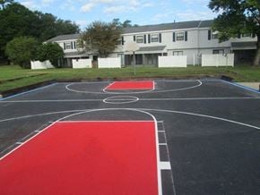 Jacksonville apartment for rent - a black and red basketball court in front of a building
