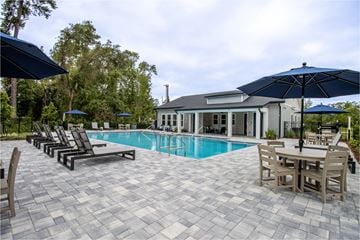 Jacksonville apartment for rent - A pool area with a table and chairs and umbrellas.